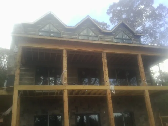 Dormers and porch framing on a large log home under construction — Roof Coating work by our crew in Johnston