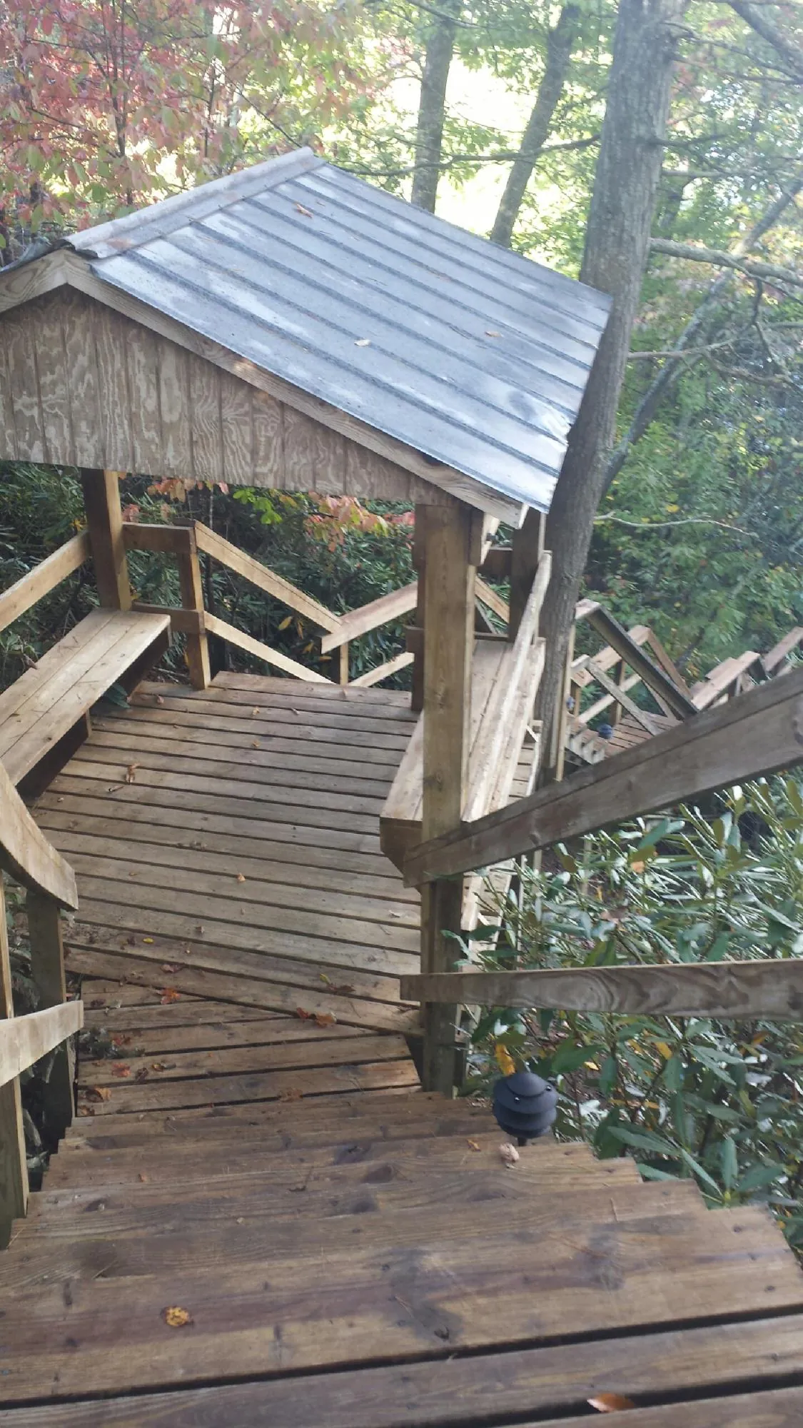 Metal roofed shelter over wooden steps on a wooded walkway — Skylight Repair & Installation work by our crew in Johnston