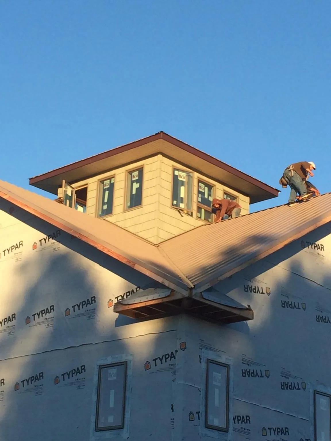 Roofers working around a rooftop cupola on a new metal roof at sunset — Roof Waterproofing in Johnston by Roofing Brothers